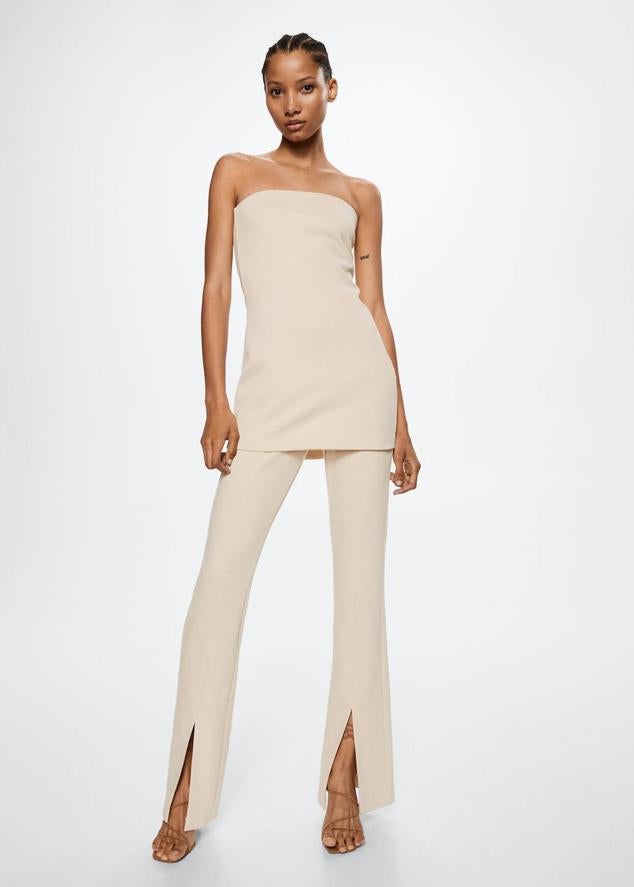 Pantalón en tejido fluido con tiro alto, pernera recta y abertura en el bajo, color crudo, de Mango. Están disponibles a 25,99 euros.
