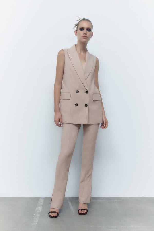 Pantalón de vestir con tiro alto, perneras entalladas y bajo terminado en abertura, en color camel claro, de Zara. Hazte con él a 29,95 euros.