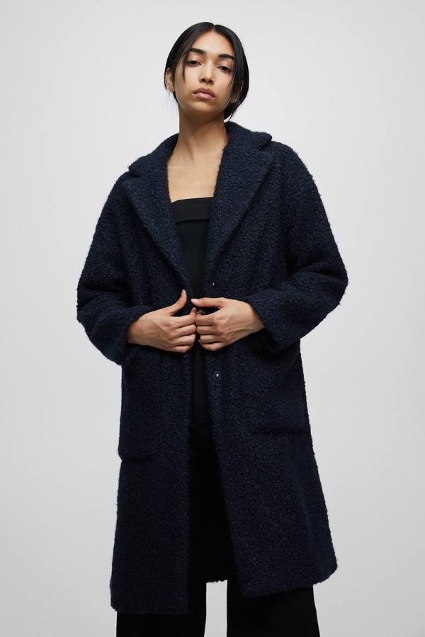Abrigo largo en tejido bouclé con cuello solapa, bolsillos laterales y cierre por botones a presión, en azul oscuro, de Pull&Bear. Hazte con él a 39,99 euros.