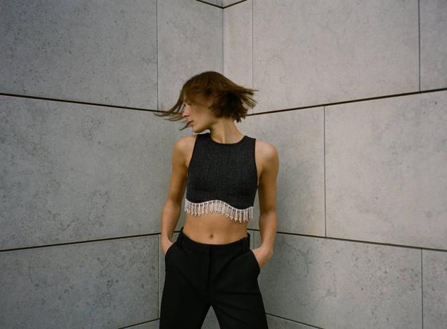 Top seamless con manga sisa, cuello redondo y adorno de colgantes de brillantes en el bajo, color negro, de Zara. Tiene un precio de 22,95 euros.