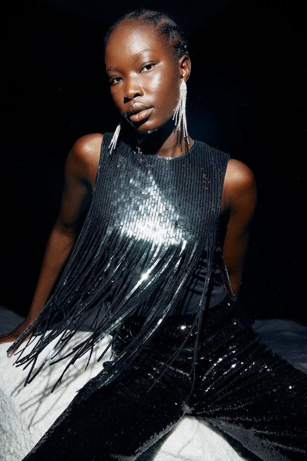 Top en tejido de lentejuelas con cuello redondo, manga sisa y detalles de flecos largos, color negro, de H&M. Está disponible a 24,99 euros.