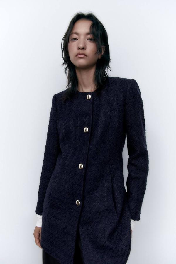 Chaqueta larga en tejido de estructura con coste entallado, cuello redondo, manga larga, bolsillos y cierre de botones, en azul marino, de Zara. Puedes encontrarla por 59,95 euros.