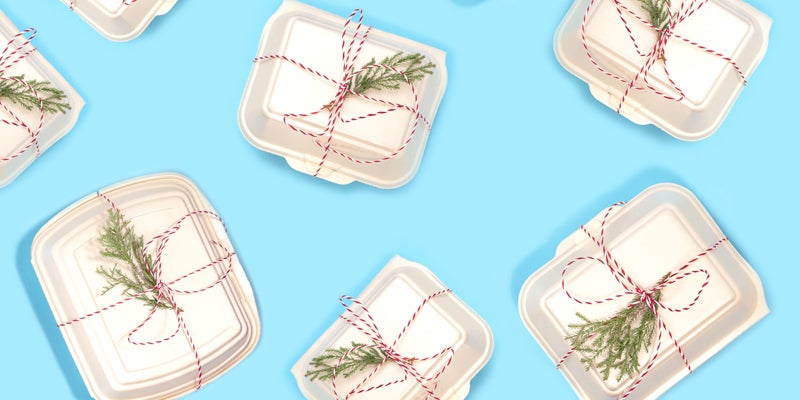 Pattern made of Food Delivery Boxes with green Christmas tree branches on pastel blue background. Concept of online food ordering with  home delivery, food order, takeaway. Copy space, close up, flat lay.
