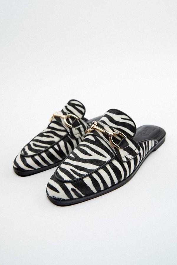 Mocasines destalonados en tejido de piel con suela plana, detalle de hebilla en el delantero y animal print de cebra en blanco y negro, de Zara. Puedes comprarlos por 49,95 euros.