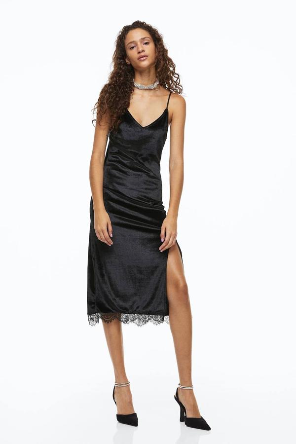 Vestido lencero midi en tejido de terciopelo con escote de pico, tirantes finos, abertura en el bajo y detalles de encaje, en negro, de H&M. Está disponible a 29,99 euros.