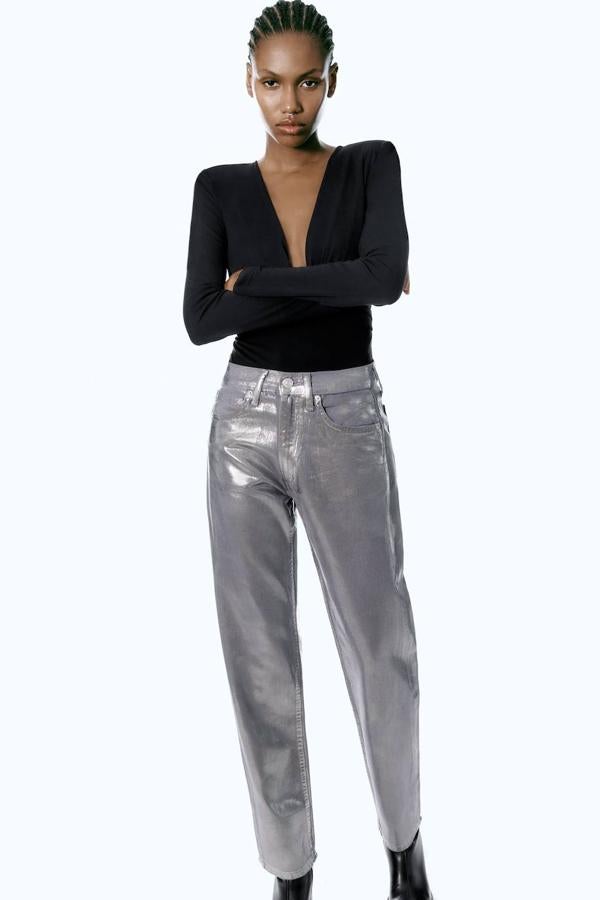 Jeans encerados con acabado metalizado, tiro medio, trabillas y cinco bolsillos, tono plata.