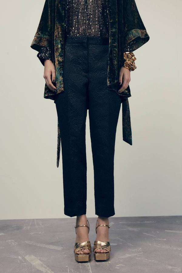 Pantalón tobillero en tejido brocado con tiro alto, bolsillos y perneras acomodadas al cuerpo, de Zara. Encuéntralo rebajado a 19,99 euros.