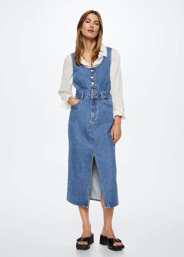 Vestido midi tipo pichi en tejido denim con tirantes anchos, escote redondo, cierre de botones, bolsillos y abertura en el bajo, de Mango. Su coste en rebajas es de 29,99 euros.