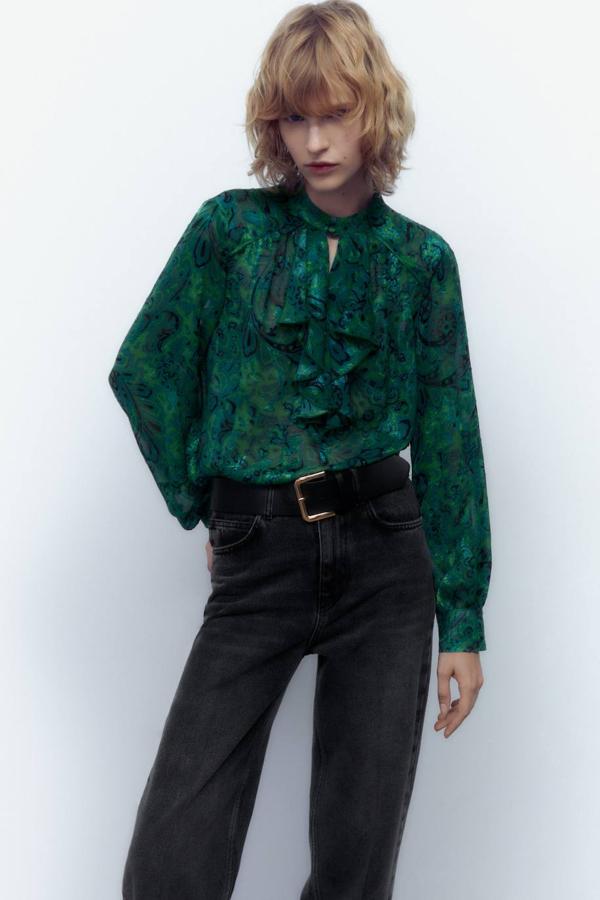 Blusa en tejido fluido estampado con detalle de volantes, manga larga abullonada y cuello subido, en verde, de Zara. Está disponible con descuento a 17,99 euros.