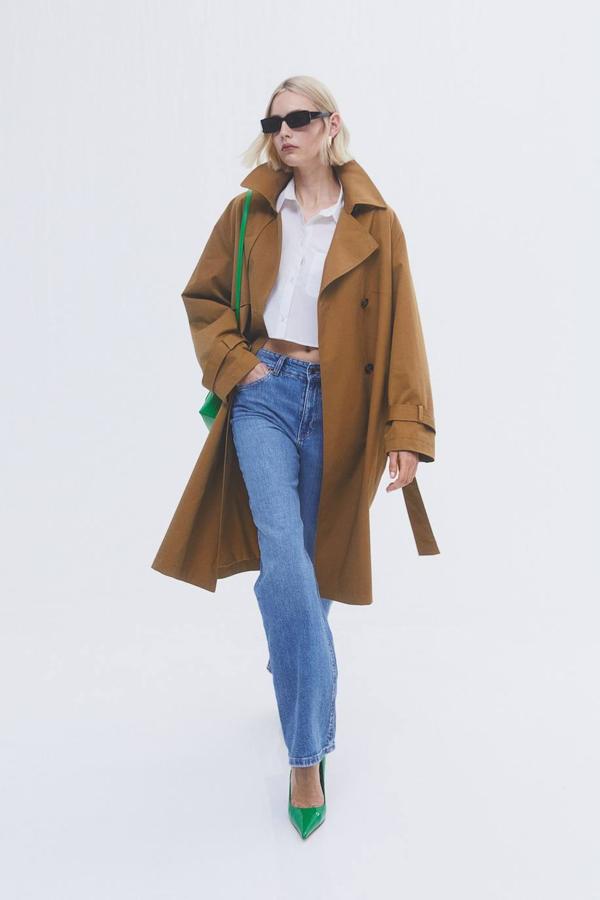 Trench en tejido de algodón con cuello solapa amplio, cierre cruzado por doble botonadura, mangas largas, bolsillos y cinturón, color marrón, de H&M. Lo encontrarás a 59,99 euros.