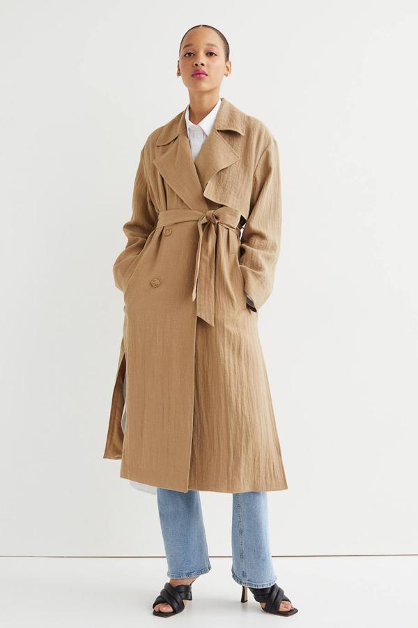 Gabardina larga en tejido ligero de crepé con corte relajado, manga larga, cuello solapa, cierre cruzado, bolsillos y cinturón, en camel, de H&M. Cuesta 59,99 euros.