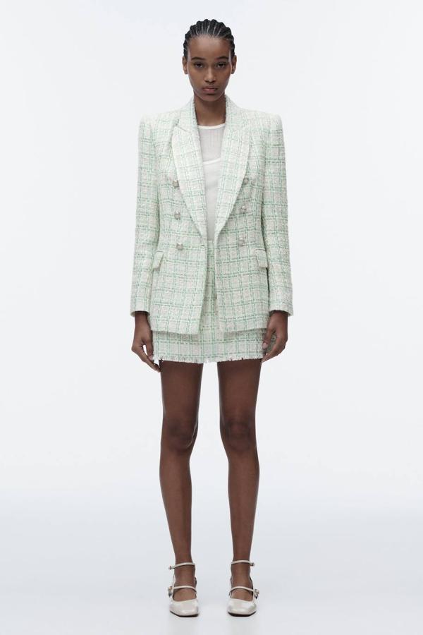Conjunto de tweed compuesto por blazer de doble botonadura y falda pantalón desflecada, en print a cuadros tonos verde y rosa, de Zara. Consíguelo por 55,95 euros y 25,95 euros.