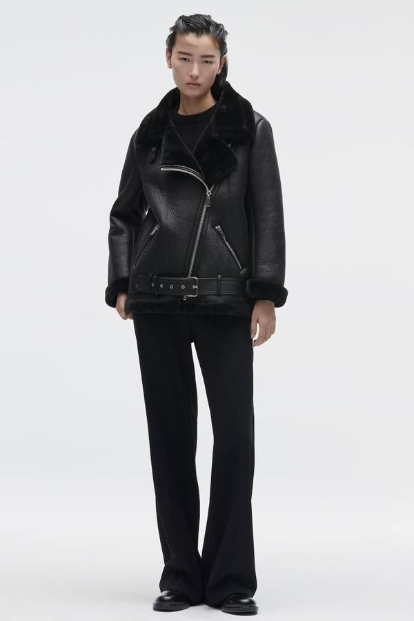 Cazadora doble faz en tejido de piel texturizado con cierre cruzado, cuello solapa amplio, bolsillos con cremallera y cinturón, color negro, de Zara. La encontrarás a 79,95 euros.