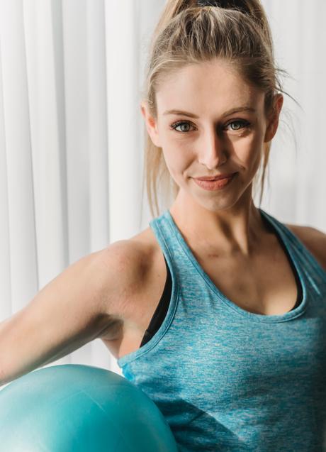 Imagen - Mujer sonriente con pelota deportiva/PEXELS
