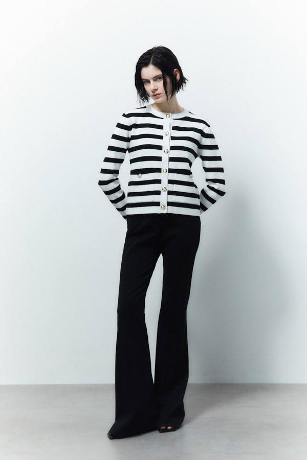 Chaqueta de punto con cuello redondo, manga larga, botones dorados y estampado a rayas en blanco y negro, de Sfera. Puedes conseguirla a 29,99 euros.