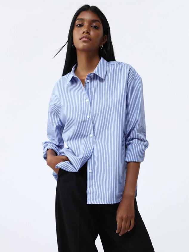 Camisa de popelín con corte holgado, cuello solapa, mangas largas y cierre de botones, en estampado a rayas finas blanco y azul, de Lefties. Cuesta 8,99 euros.