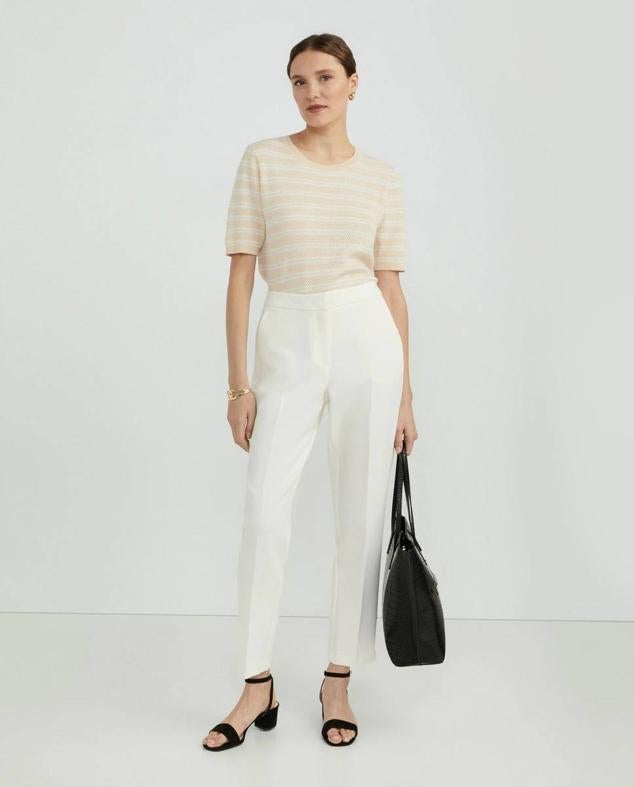 Pantalón de traje con perneras acomodadas al cuerpo, tiro alto, bolsillos y raya marcada, color blanco, de Woman El Corte Inglés. Puedes encontrarlo a 45,99 euros.