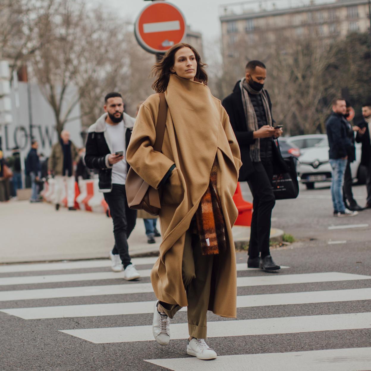Una mujer caminando con zapatillas blancas.