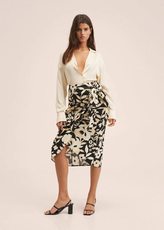 Falda midi tipo pareo con diseño cruzado, detalle de lazada y abertura en el bajo, en estampado de flores bicolor, crudo y negro. Su precio es de 20,99 euros.