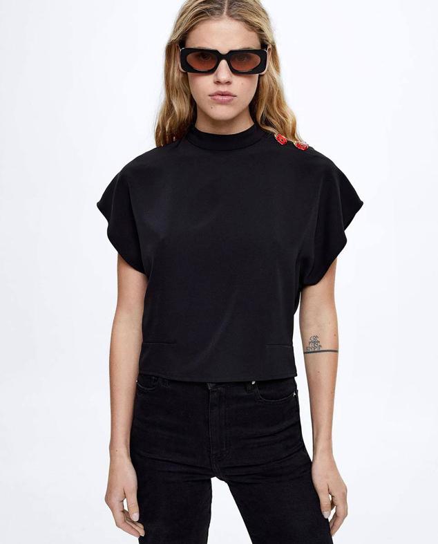 Camiseta de manga corta anchas, cuello subido y detalle de broche de mariquitas en el hombro, color negro, de Parfois. Podrás comprarla por 29,99 euros.