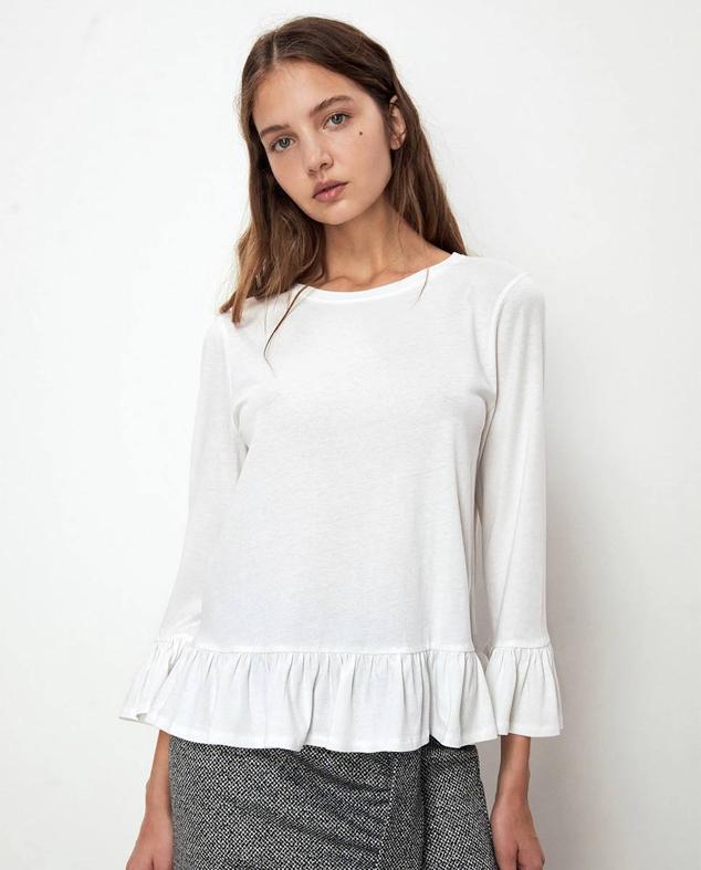Camiseta de manga larga con cuello redondo y terminaciones en volantes, color blanco, de Sfera. Te costará 9,99 euros.