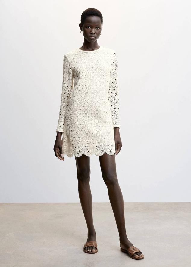 Vestido corto de crochet con cuello redondo, manga larga y bajo festoneado, en blanco, de Mango. Lo encontrarás por 59,99 euros.