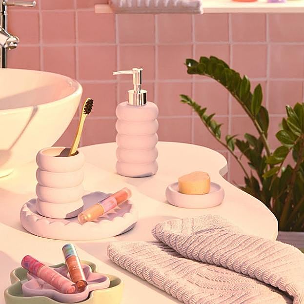 Imagen principal - Los accesorios de baño en rosa empolvado o verde menta están disponibles desde 4.50 euros. El difusor grande de cedro y vainilla cuesta 3.50 euros y el pequeño, 0.80 euros. La vela verde con diseño de caras cuesta 7 euros.