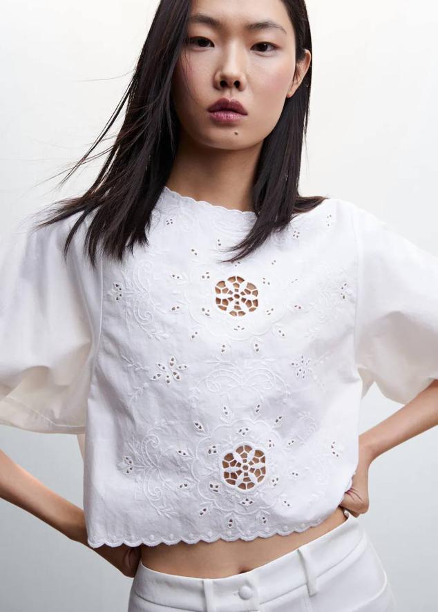 Blusa con bordado suizo, manga corta tipo globo, cuello redondo, detalles florales y bajo festoneado, de Mango. Hazte con ella por 27,99 euros.