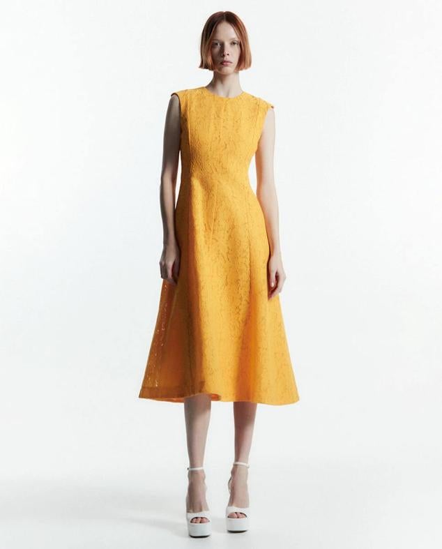 Vestido midi de encaje con falda de vuelo, manga tipo sisa y cuello redondo, tono amarillo, de Sfera. Puedes comprarlo a 49,99 euros.