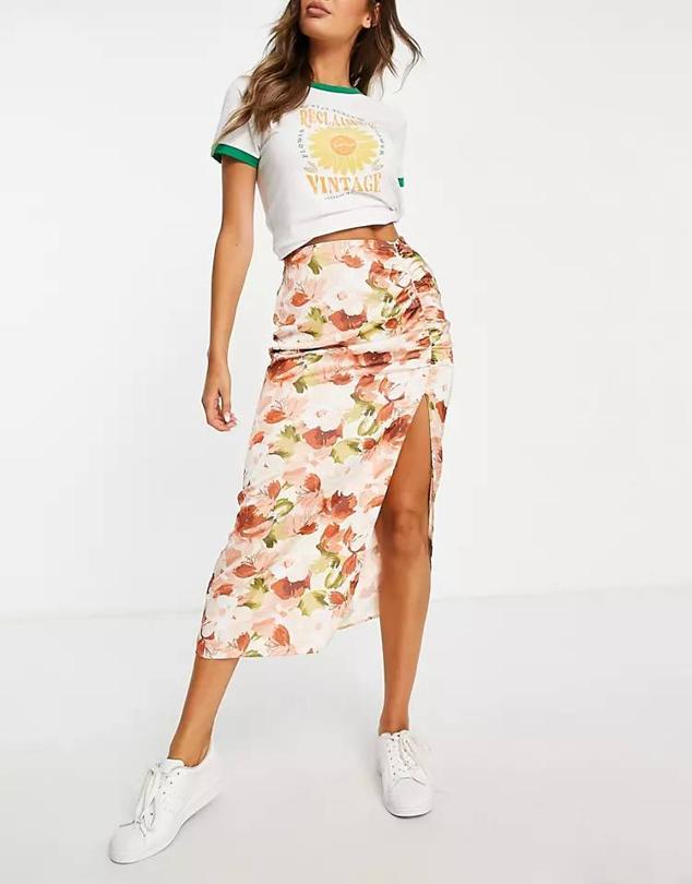 Falda midi en tejido de satén con tiro alto, detalle fruncido y abertura en el bajo, en floral print, de Abercrombie & Fitch. Te costará 85 euros en Asos.