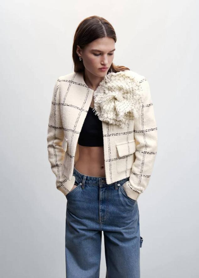 Chaqueta de tweed con manga larga, cuello redondo, detalle de maxi flor y estampado a cuadros, tono crudo de Mango. Consíguela por 79,99 euros.