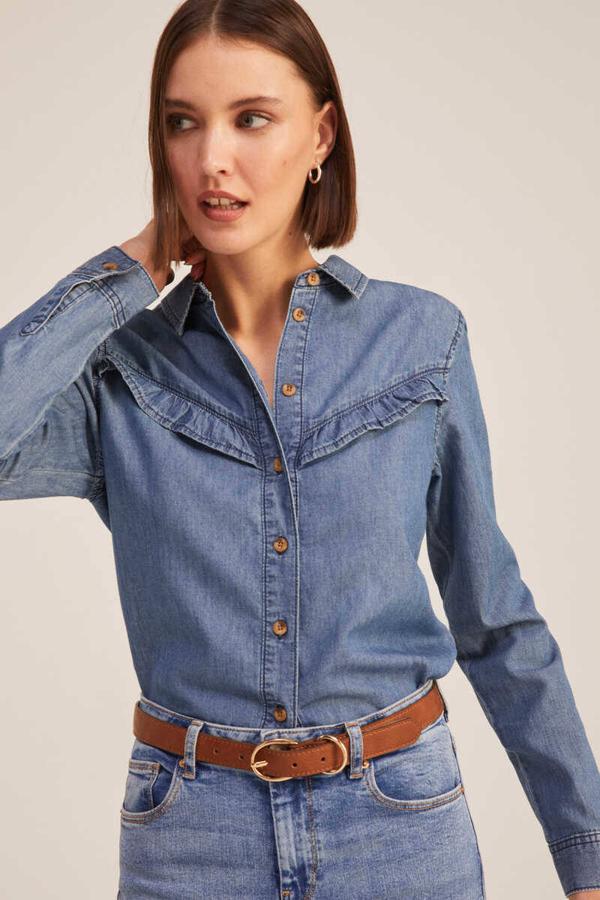 Camisa denim con manga larga, cuello solapa y detalle de volantes en el pecho, de Springfield. Hazte con ella por 29,99 euros.