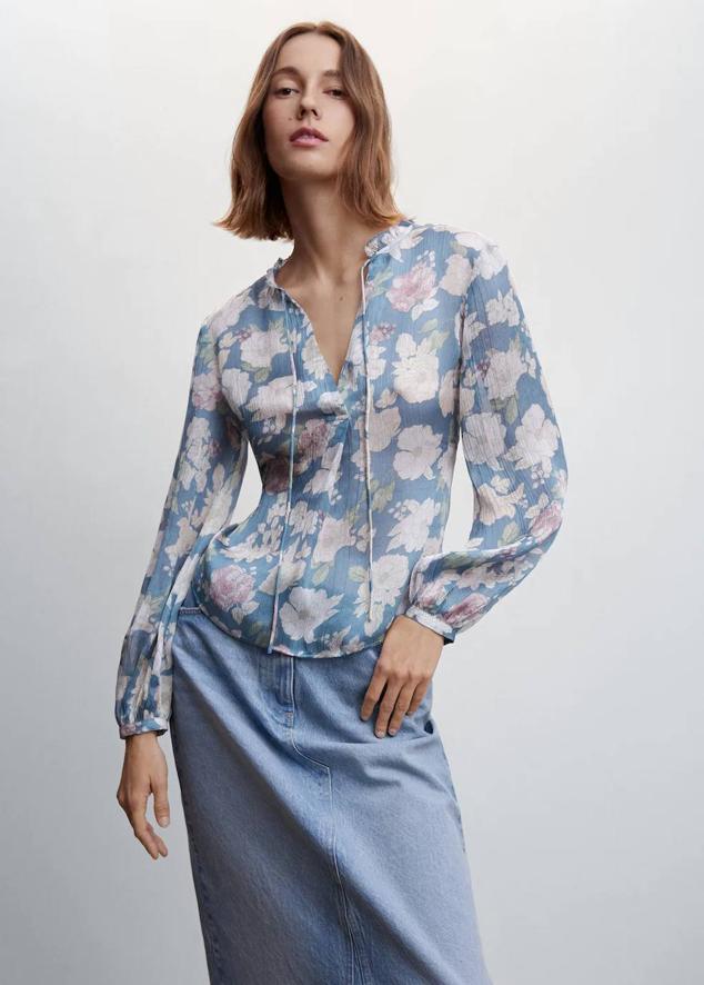 Blusa en tejido ligero texturizado con cuello redondo, cierre de lazada y manga larga, en estampado de flores azul y rosa, de Mango. Cuesta 25,99 euros.