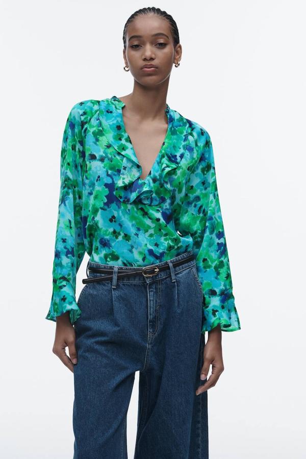 Blusa fluida con escote redondo, terminaciones en volantes y mangas largas, en floral print azul y verde, de Zara. Puedes encontrarla a 25,95 euros.