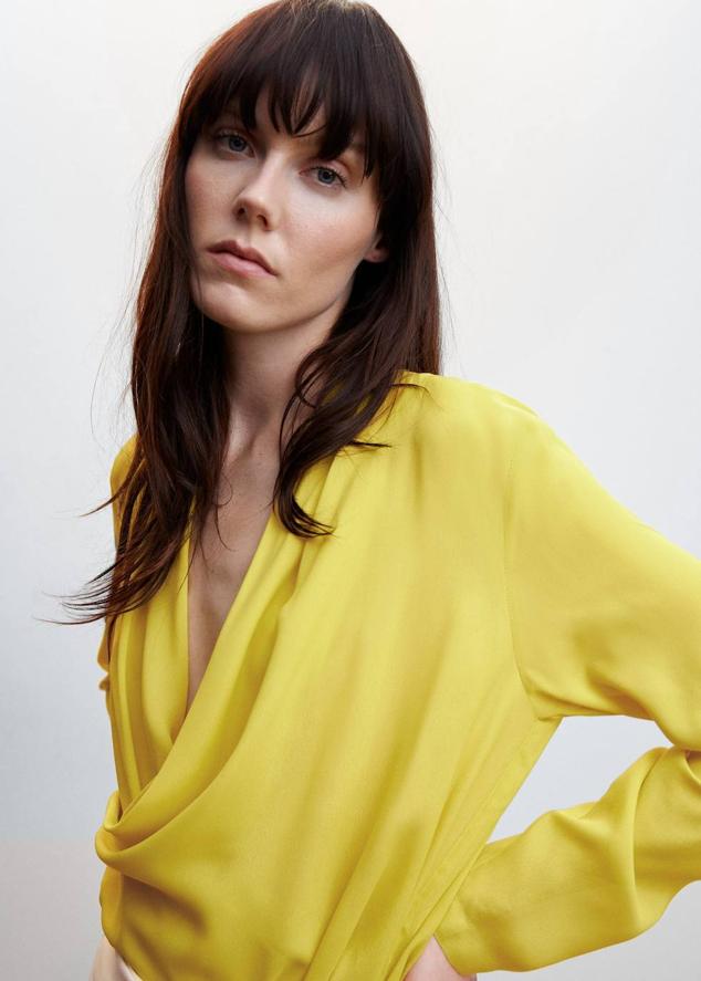 Blusa en tejido vaporoso con escote cruzado drapeado y mangas largas, color amarillo, de Mango. Hazte con ella por 35,99 euros.