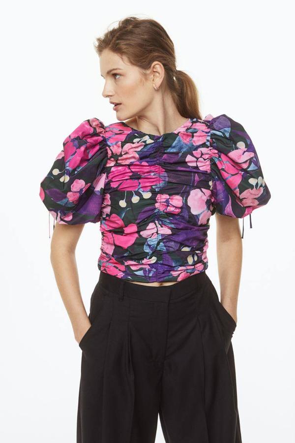 Blusa entallada con cuello redondo, pliegues y manga corta abullonada con lazadas, en estampado de flores morado y rosa, de H&M. Hazte con ella a 24,99 euros.