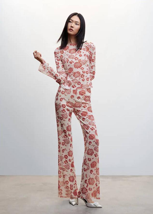 Pantalón en tejido elástico con tiro alto y perneras ajustadas terminadas en campana, en estampado de flores blanco y rojo. Te costará 27,99 euros.