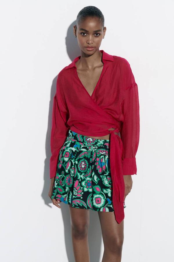 Falda corta en tejido de lino con tiro alto fruncido y bajo acabado en evasé, en maxi estampado multicolor. Está disponible a 25,95 euros.