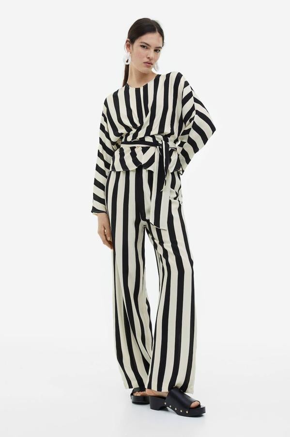 Pantalón en tejido fluido con corte relajado, perneras amplias, tiro alto y cintura elástica, en estampado a rayas gruesas blanco y negro, de H&M. Lo encontrarás a 34,99 euros.
