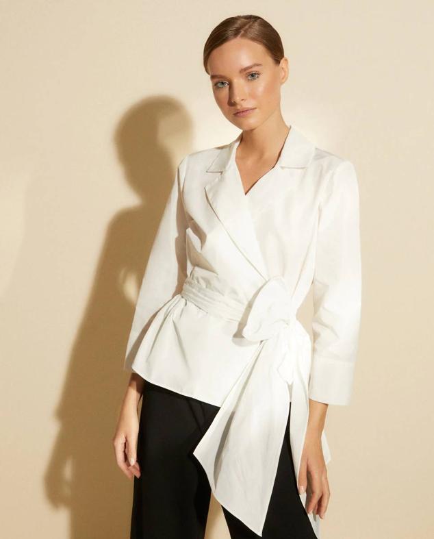 Blusa cruzada con cuello solapa con muesca, manga larga y maxi lazo frontal, en blanco, de Woman El Corte Inglés. Te costará 99,99 euros.