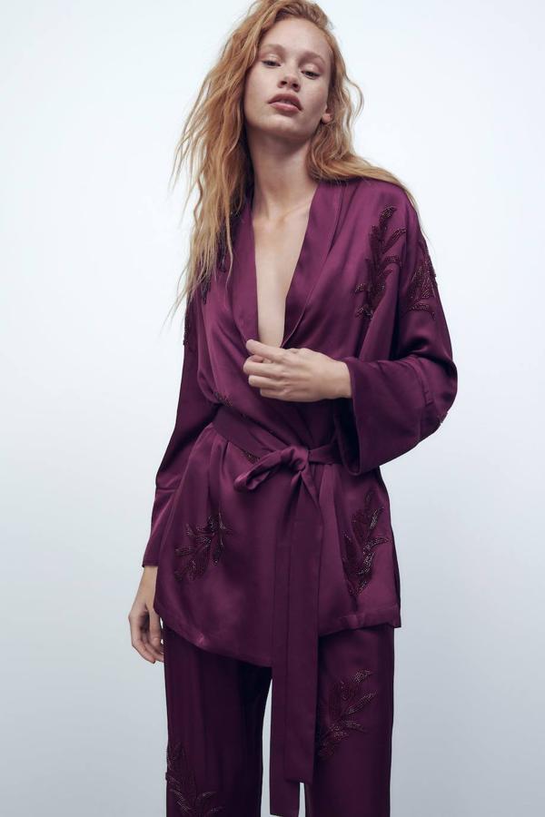 Blusa tipo kimono en tejido satinado con manga larga, cuello solapa, cinturón de lazada y bordados a tono con abalorios, color morado. Puedes comprarla a 69,95 euros.