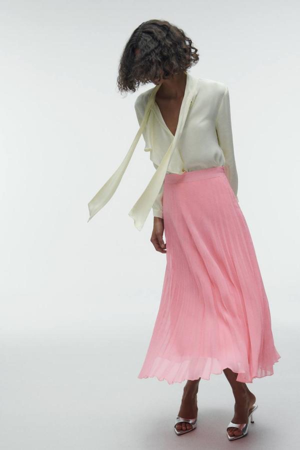 Falda midi en tejido vaporoso plisado con tiro alto y vuelo, color rosa, de Zara. Cómprala a 29,95 euros.
