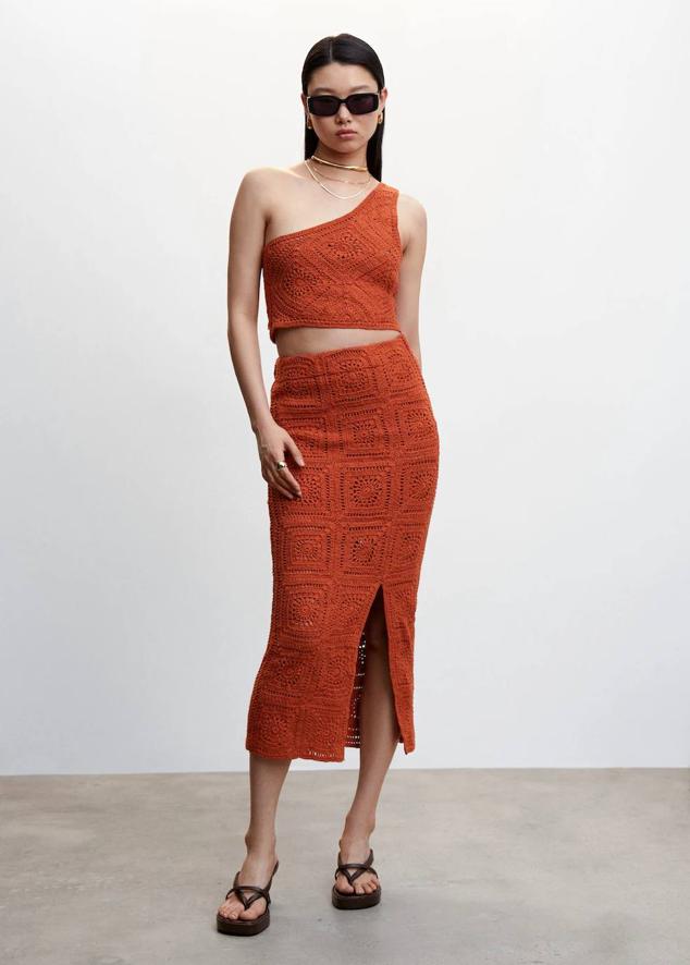 Conjunto de crochet con crop top asimétrico y falda midi de tubo con abertura, tono rojo anaranjado, de Mango. Puedes encontrarlo a 39,99 euros y 89,99 euros.