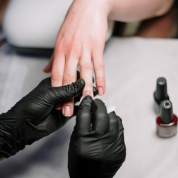 Profesional en proceso de quitar uñas de gel
