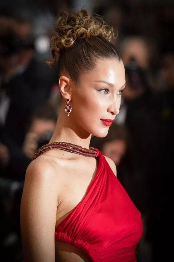 Las chicas de  pelo rizado  también pueden ir cómodas, modernas y favorecidas con este peinado. Procuraremos realizar un moño alto, peinando hacia arriba con los dedos o con un peine de púas anchas. Para sujetarlo, podemos usar horquillas, una pinza grande, gomilla o scrunchies. Y, si quieres un acabado a la moda. La base del pelo quedará muy tirante, con gel fijador.