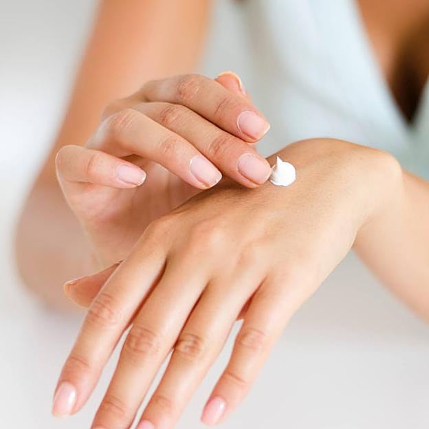 Mujer aplicando crema reparadora de manos ásperas