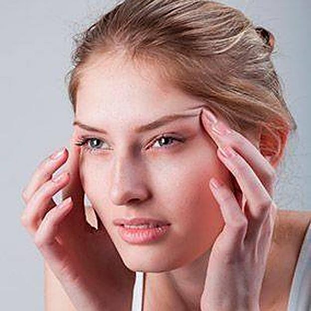 Mujer examinando patas de gallo en los ojos