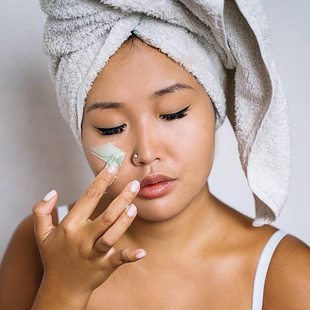 Mujer aplicando crema en la cara