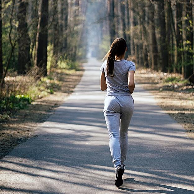 Mujer de espaldas practicando running en un parque.