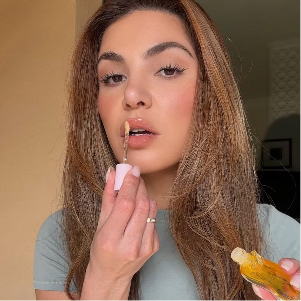 Una mujer utilizando el lip oil de Gisou.